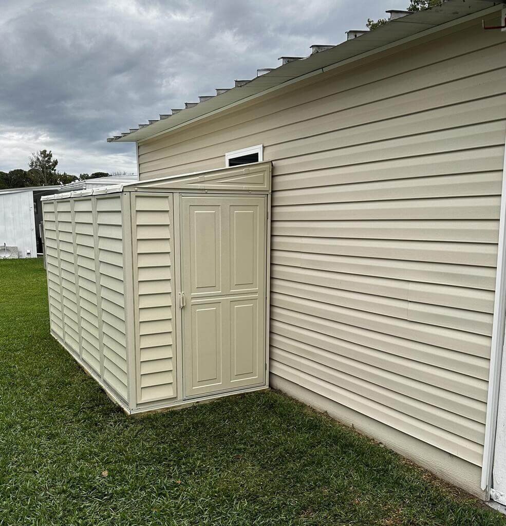 Duramax 4x10 SideMate ivory vinyl shed against a house wall